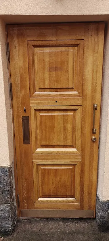 Vaaleanruskea, kunnostettu puuovi, jossa on kolme paneelia, messinkinen vedin ja postiluukku.